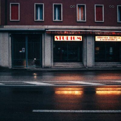 Strada di Roma illuminata da insegne neon di notte dopo la pioggia