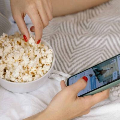 ragazza che guarda il telefono e mangia popcorn