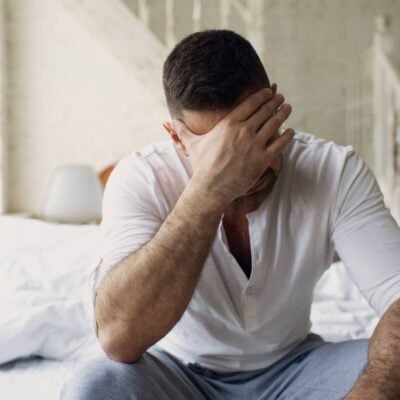 Un padre separato seduto sul letto della sua nuova casa