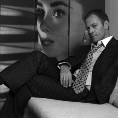 rocco siffredi in giacca e cravatta seduto su un divano