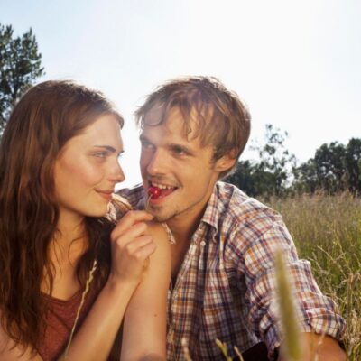 due ragazzi seduti su un prato mangiano una ciliegia